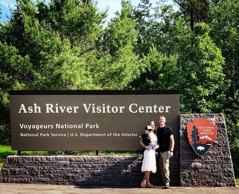 Family photo in front of the Ash River Visitor Center Sign at voyageurs