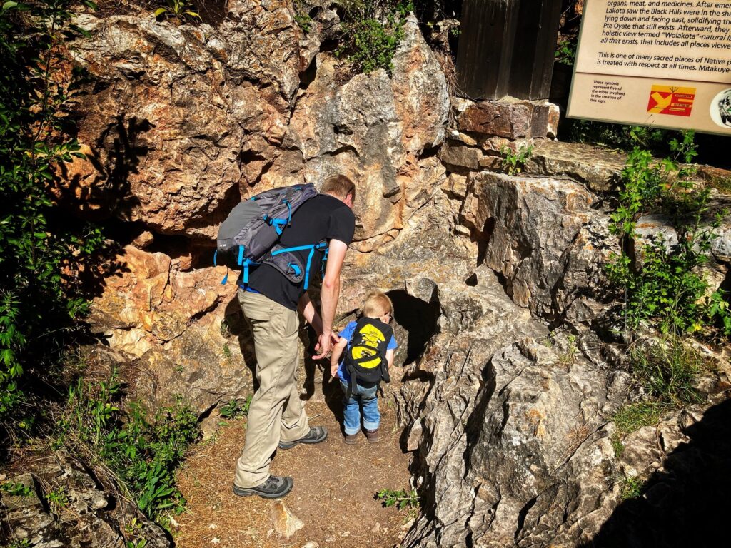 Father and son leaning into a small cave opening