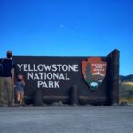 Masked family at yellowstone entrance sign