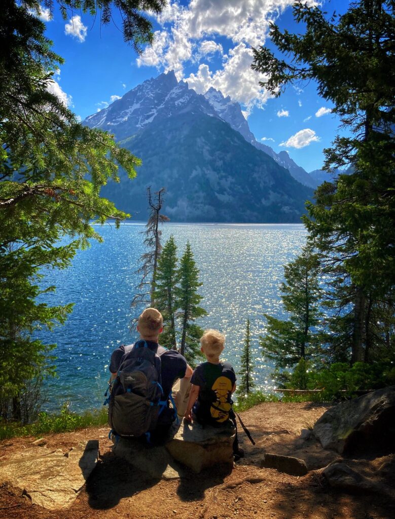 Father in son in front of lake with mountain.