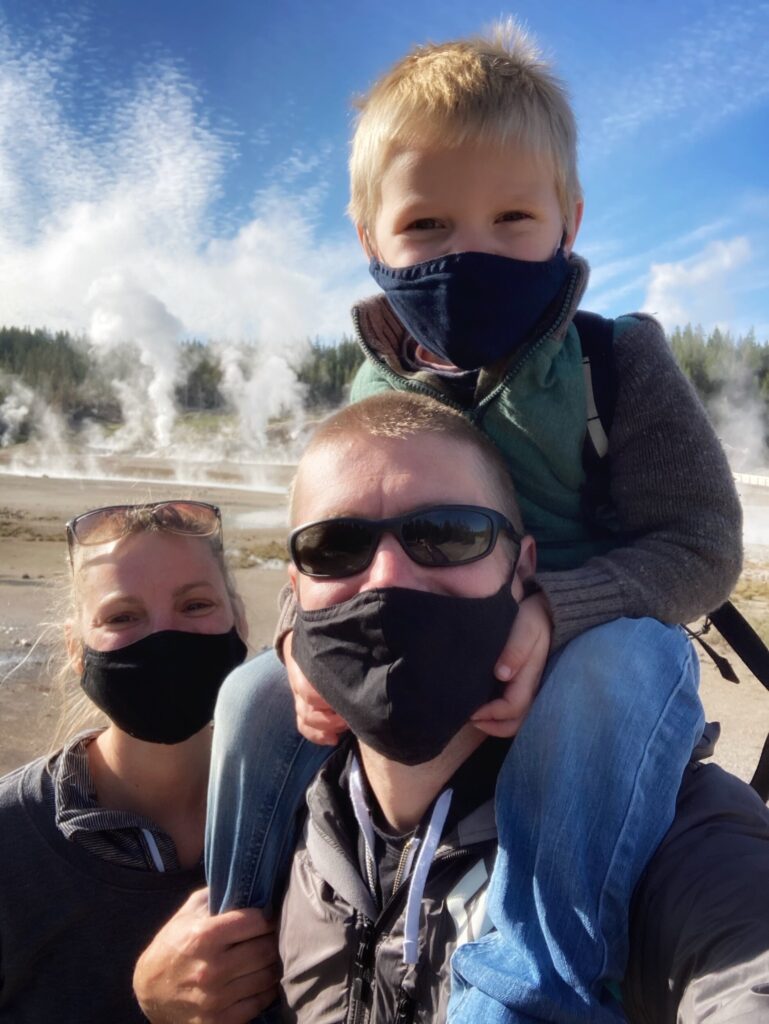 Family in masks in front of steam outside
