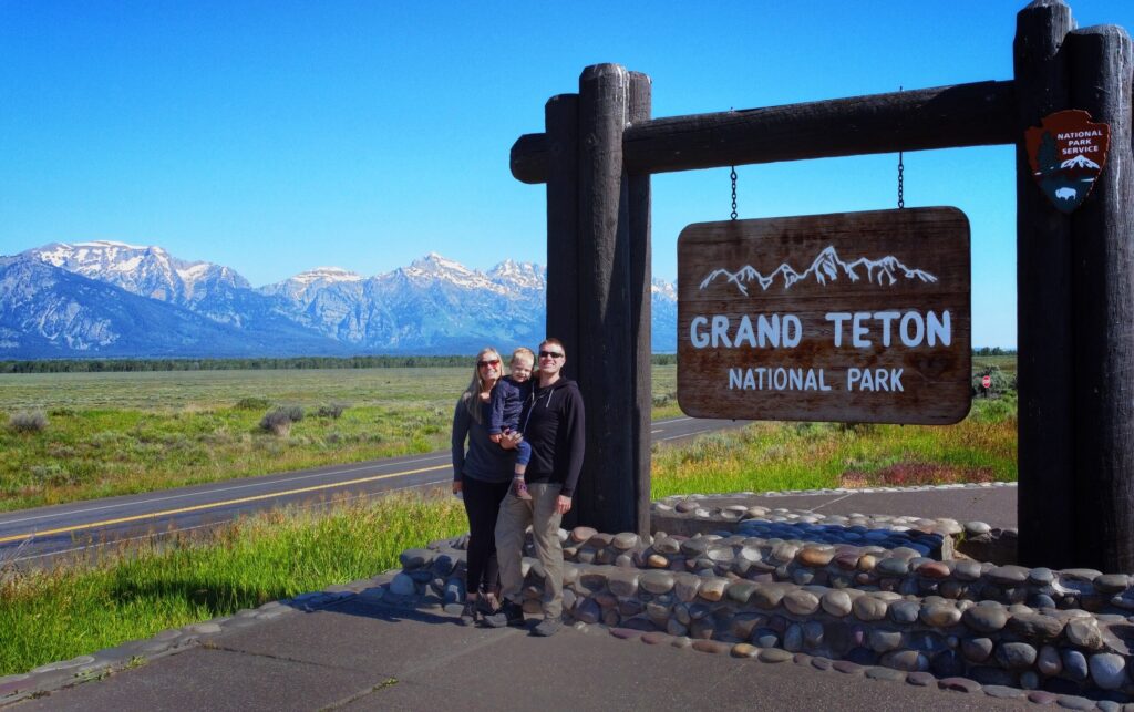 Family in front of Grand Teton entrance sign